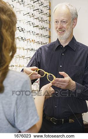 Smiling owner giving eyeglasses to woman at store View Large Photo Image Stock Image - Smiling owner giving eyeglasses to woman at store. Fotosearch
