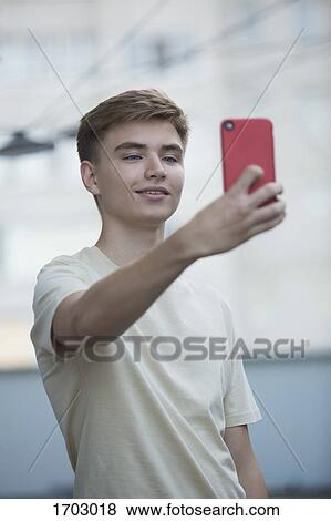 Smiling teenage boy taking selfie from mobile phone View Large Photo Image Stock Photo - Smiling teenage boy taking selfie from mobile phone. Fotosearch