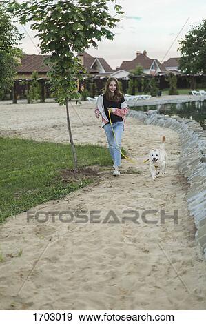 Smiling teenage girl walking with dog on sand View Large Photo Image Stock Photo - Smiling teenage girl walking with dog on sand. Fotosearch