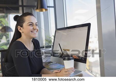 Smiling woman drinking coffee and using computer at internet cafe View Large Photo Image Stock Photography - Smiling woman drinking coffee and using computer at internet cafe. Fotosearch