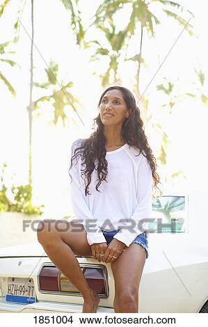 Smiling woman in shorts leaning on car View Large Photo Image Picture - Smiling woman in shorts leaning on car. Fotosearch