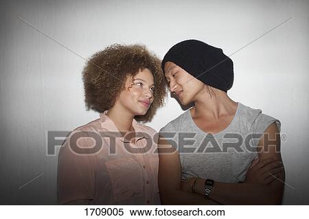 Smiling young couple standing against wall View Large Photo Image Stock Photography - Smiling young couple standing against wall. Fotosearch