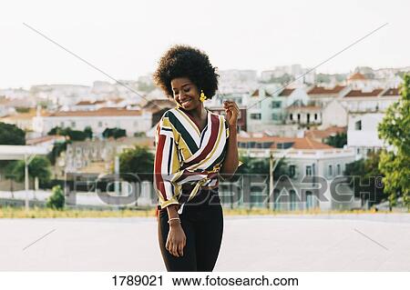 Stock Image - Smiling young woman standing on sunny street, Belem, Lisbon, Portugal. Fotosearch