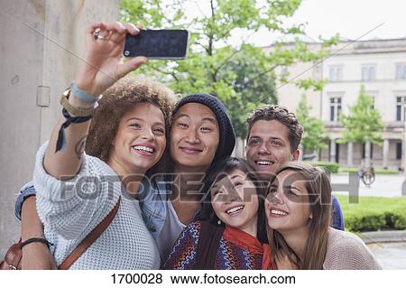 Smiling young woman taking selfie with multi-ethnic friends, Berlin, Germany View Large Photo Image Stock Photo - Smiling young woman taking selfie with multi-ethnic friends, Berlin, Germany. Fotosearch
