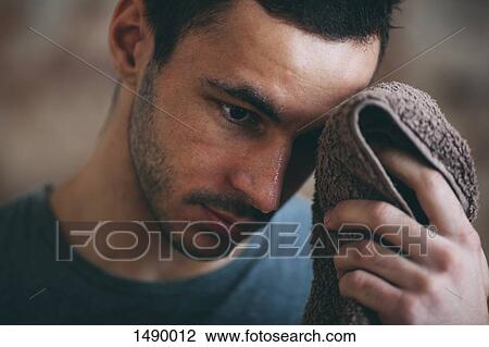Sporty man wiping sweat on forehead at gym View Large Photo Image Stock Image - Sporty man wiping sweat on forehead at gym. Fotosearch