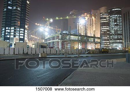 Street against illuminated construction site and buildings at night View Large Photo Image Stock Photo - Street against illuminated construction site and buildings at night. Fotosearch