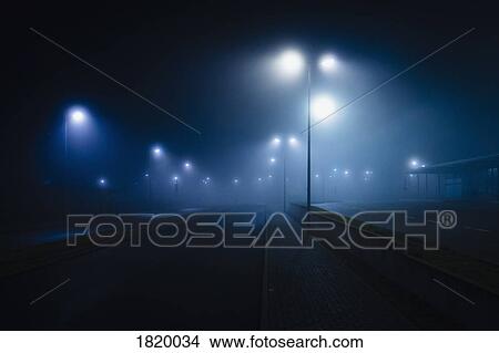 Street lamps illuminated over foggy, vacant road View Large Photo Image Picture - Street lamps illuminated over foggy, vacant road. Fotosearch