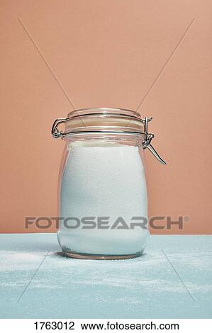 Stock Image - Sugar in jar and sprinkled over counter. Fotosearch
