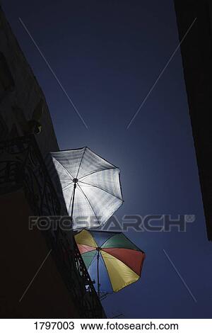 Sun shining behind striped and multicolor beach umbrellas on balcony below blue sky View Large Photo Image Stock Image - Sun shining behind striped and multicolor beach umbrellas on balcony below blue sky. Fotosearch