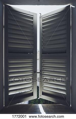 Stock Image - Sunlight behind white wood shutters. Fotosearch