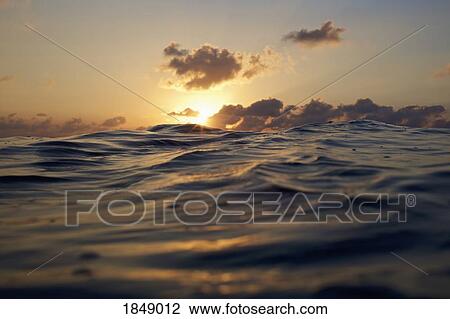 Stock Image - Sunset over tranquil ocean. Fotosearch