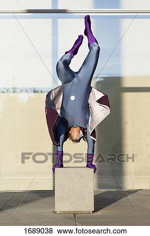 Superhero doing handstand on concrete against glass wall View Large Photo Image Stock Photo - Superhero doing handstand on concrete against glass wall. Fotosearch