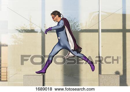 Superhero jumping on concrete against glass wall View Large Photo Image Stock Photo - Superhero jumping on concrete against glass wall. Fotosearch