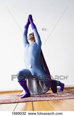 Superhero practicing yoga on carpet against white wall View Large Photo Image Stock Image - Superhero practicing yoga on carpet against white wall. Fotosearch