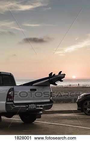 Stock Image - Surfboards in truck bed parked along beach at sunset, Newport Beach, California, USA. Fotosearch