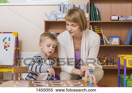 Teacher sitting and teaching student in preschool View Large Photo Image Stock Photography - Teacher sitting and teaching student in preschool. Fotosearch