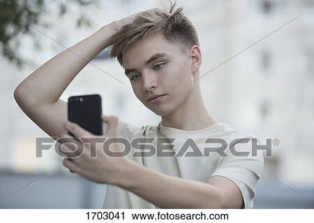 Teenage boy taking selfie from mobile phone with hand in hair View Large Photo Image Stock Image - Teenage boy taking selfie from mobile phone with hand in hair. Fotosearch