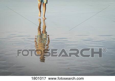 Teenage boy walking on wet sand beach View Large Photo Image Stock Photo - Teenage boy walking on wet sand beach. Fotosearch