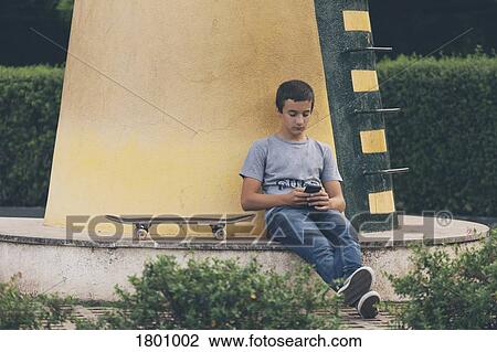 Teenage boy with skateboard using smart phone View Large Photo Image Stock Image - Teenage boy with skateboard using smart phone. Fotosearch