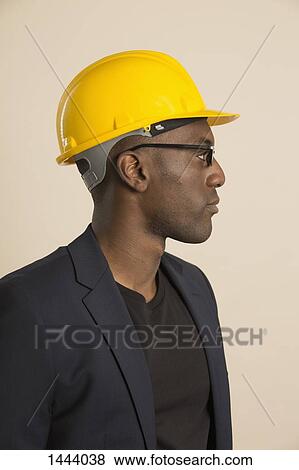 Stock Photo - Thoughtful architect looking away against colored background. Fotosearch