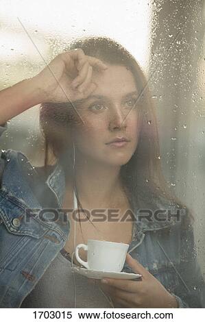 Thoughtful beautiful woman holding coffee cup while looking through window View Large Photo Image Stock Photography - Thoughtful beautiful woman holding coffee cup while looking through window. Fotosearch