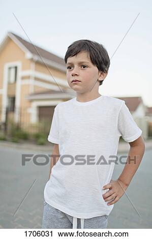 Thoughtful boy standing with hand on hip in town against clear sky View Large Photo Image Stock Image - Thoughtful boy standing with hand on hip in town against clear sky. Fotosearch