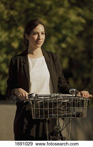 Thoughtful businesswoman looking away while standing with bicycle on sunny day View Large Photo Image Stock Photo - Thoughtful businesswoman looking away while standing with bicycle on sunny day. Fotosearch