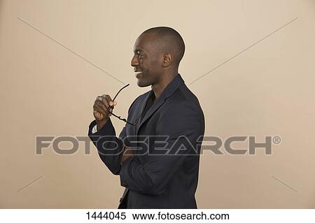 Thoughtful man smiling while looking away against colored background View Large Photo Image Stock Photography - Thoughtful man smiling while looking away against colored background. Fotosearch