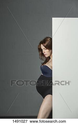 Thoughtful pregnant woman behind screen against gray background View Large Photo Image Stock Photo - Thoughtful pregnant woman behind screen against gray background. Fotosearch