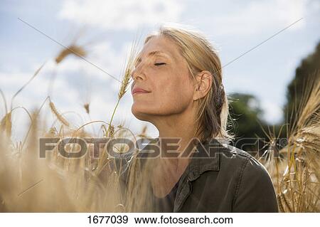 Thoughtful smiling woman with closed eyes resting amidst crops at farm on sunny day View Large Photo Image Stock Photo - Thoughtful smiling woman with closed eyes resting amidst crops at farm on sunny day. Fotosearch