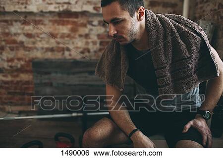 Thoughtful sporty man sitting in gym View Large Photo Image Stock Photograph - Thoughtful sporty man sitting in gym. Fotosearch