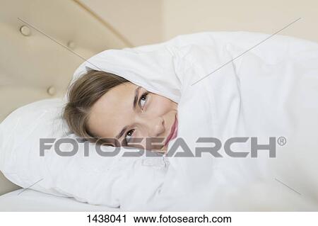 Thoughtful woman covered with duvet looking away while relaxing in bed at home View Large Photo Image Stock Image - Thoughtful woman covered with duvet looking away while relaxing in bed at home. Fotosearch