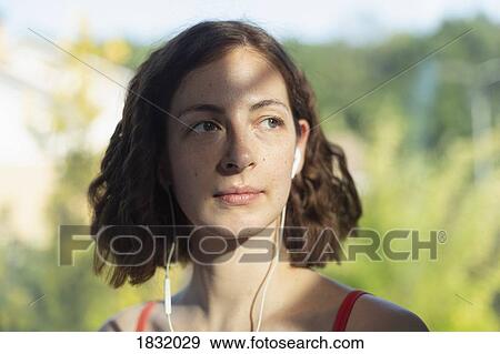 Thoughtful woman listening to music with headphones View Large Photo Image Stock Photo - Thoughtful woman listening to music with headphones. Fotosearch
