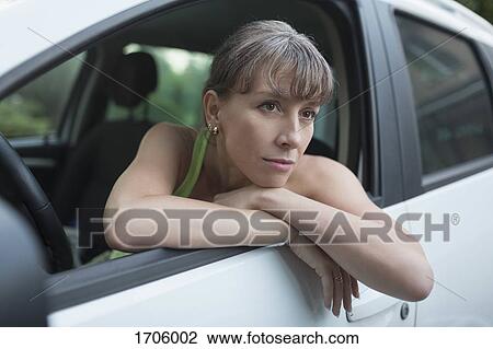 Thoughtful woman sitting in car View Large Photo Image Stock Image - Thoughtful woman sitting in car. Fotosearch