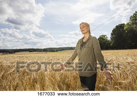 Thoughtful woman standing amidst wheat crops at farm against sky on sunny day View Large Photo Image Stock Image - Thoughtful woman standing amidst wheat crops at farm against sky on sunny day. Fotosearch