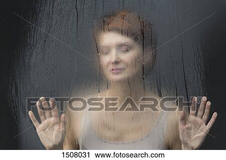 Thoughtful woman standing in front on condensed glass against black background View Large Photo Image Stock Image - Thoughtful woman standing in front on condensed glass against black background. Fotosearch