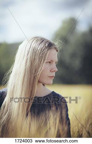 Thoughtful woman with long hair amidst grass View Large Photo Image Stock Image - Thoughtful woman with long hair amidst grass. Fotosearch