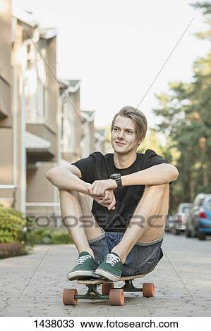Thoughtful young man sitting on skateboard outdoors View Large Photo Image Stock Image - Thoughtful young man sitting on skateboard outdoors. Fotosearch