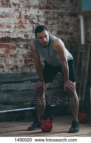 Tired athlete standing with hands on knees at gym View Large Photo Image Stock Image - Tired athlete standing with hands on knees at gym. Fotosearch