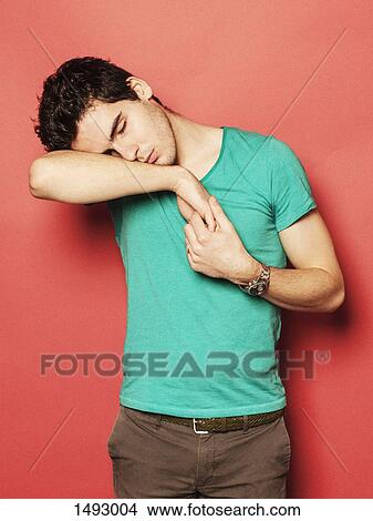 Tired young man sleeping on hand against red background View Large Photo Image Picture - Tired young man sleeping on hand against red background. Fotosearch