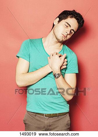 Tired young man sleeping with hands on chest against red background View Large Photo Image Stock Photo - Tired young man sleeping with hands on chest against red background. Fotosearch