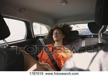 Stock Photo - Tired young woman sleeping in back seat of car. Fotosearch