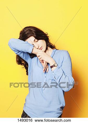 Tired young woman sleeping on hand against yellow background View Large Photo Image Stock Photograph - Tired young woman sleeping on hand against yellow background. Fotosearch