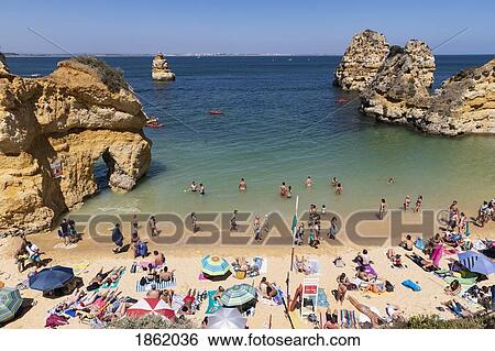 Tourists sunbathing and swimming on sunny, summer beach, Lagos, Algarve, Portugal View Large Photo Image Stock Photograph - Tourists sunbathing and swimming on sunny, summer beach, Lagos, Algarve, Portugal. Fotosearch