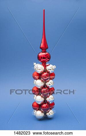 Stock Image - Tree topper on top of red and silver Christmas ornaments against blue background. Fotosearch