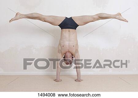 Upside down man with legs apart performing handstand yoga exercise View Large Photo Image Stock Photo - Upside down man with legs apart performing handstand yoga exercise. Fotosearch