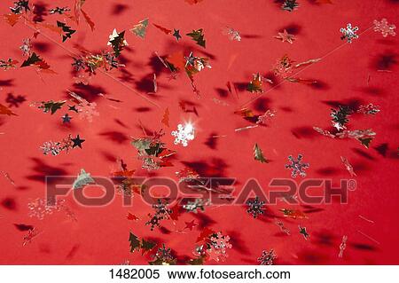 Variety of Christmas sequins falling on red background View Large Photo Image Stock Photography - Variety of Christmas sequins falling on red background. Fotosearch