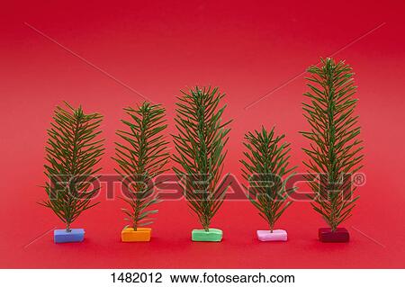 Variety of small Christmas trees on red background View Large Photo Image Stock Image - Variety of small Christmas trees on red background. Fotosearch