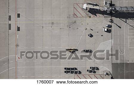 Stock Photo - View from above airport service vehicles and passenger boarding bridge on tarmac at airport. Fotosearch
