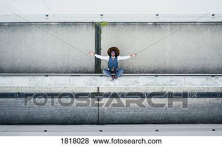 Stock Photo - View from above portrait exuberant young man on urban ledge. Fotosearch